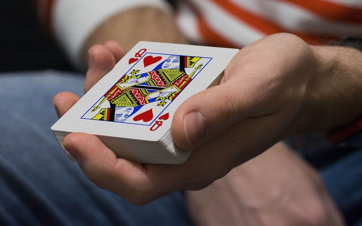 Baralho de cartas na mão com a dama de copas por cima