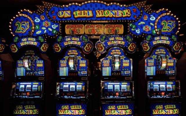 Fila de slot machines iluminadas num salão de jogo