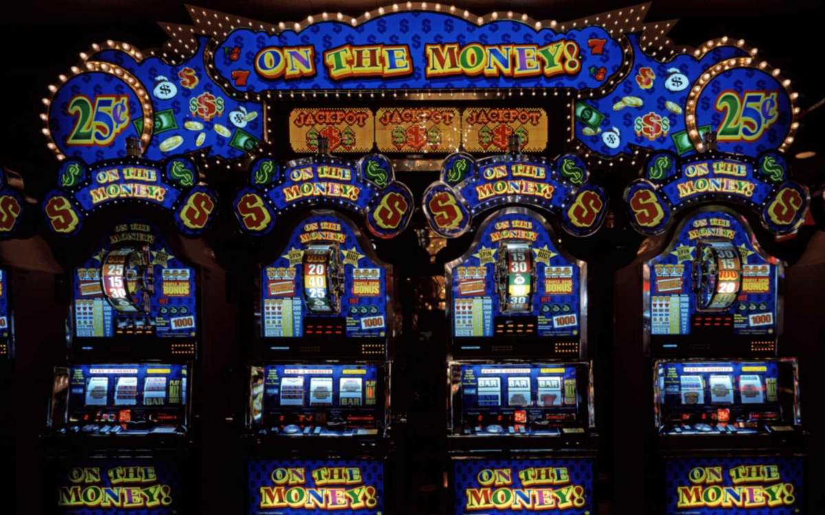 Fila de slot machines iluminadas num salão de jogo